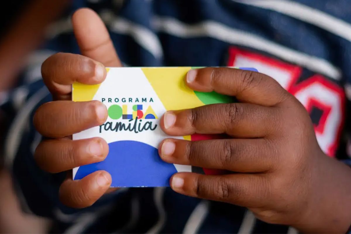 Uma criança segura o cartão do Bolsa Família