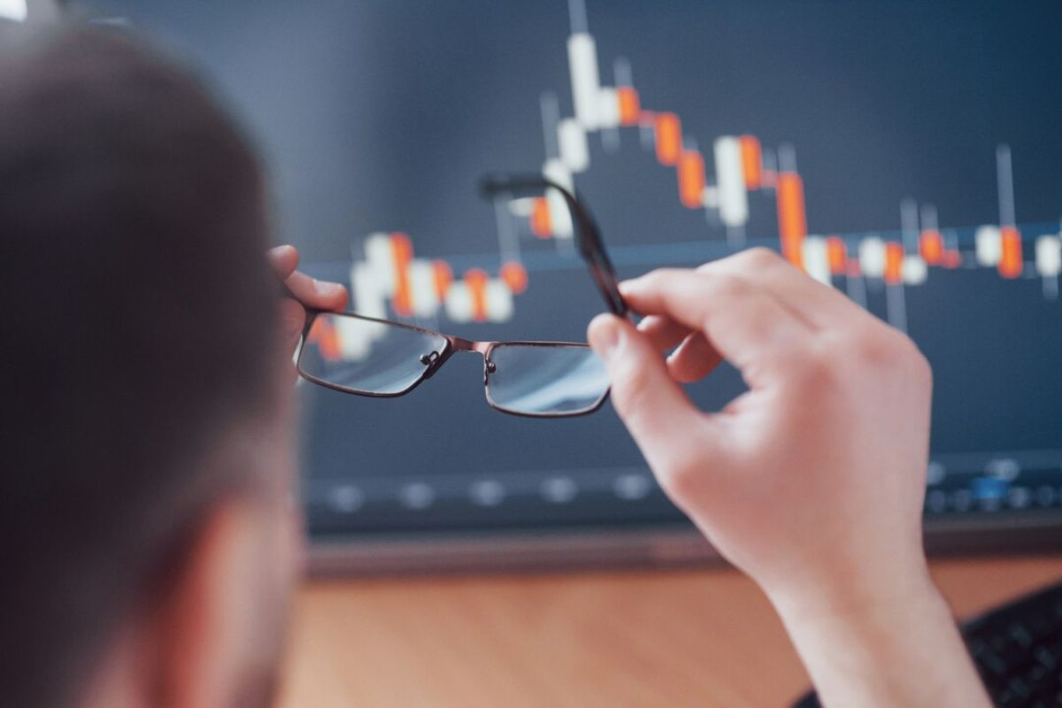 Um jovem olhando o gráfico antes começar a investir ele arruma seus óculos