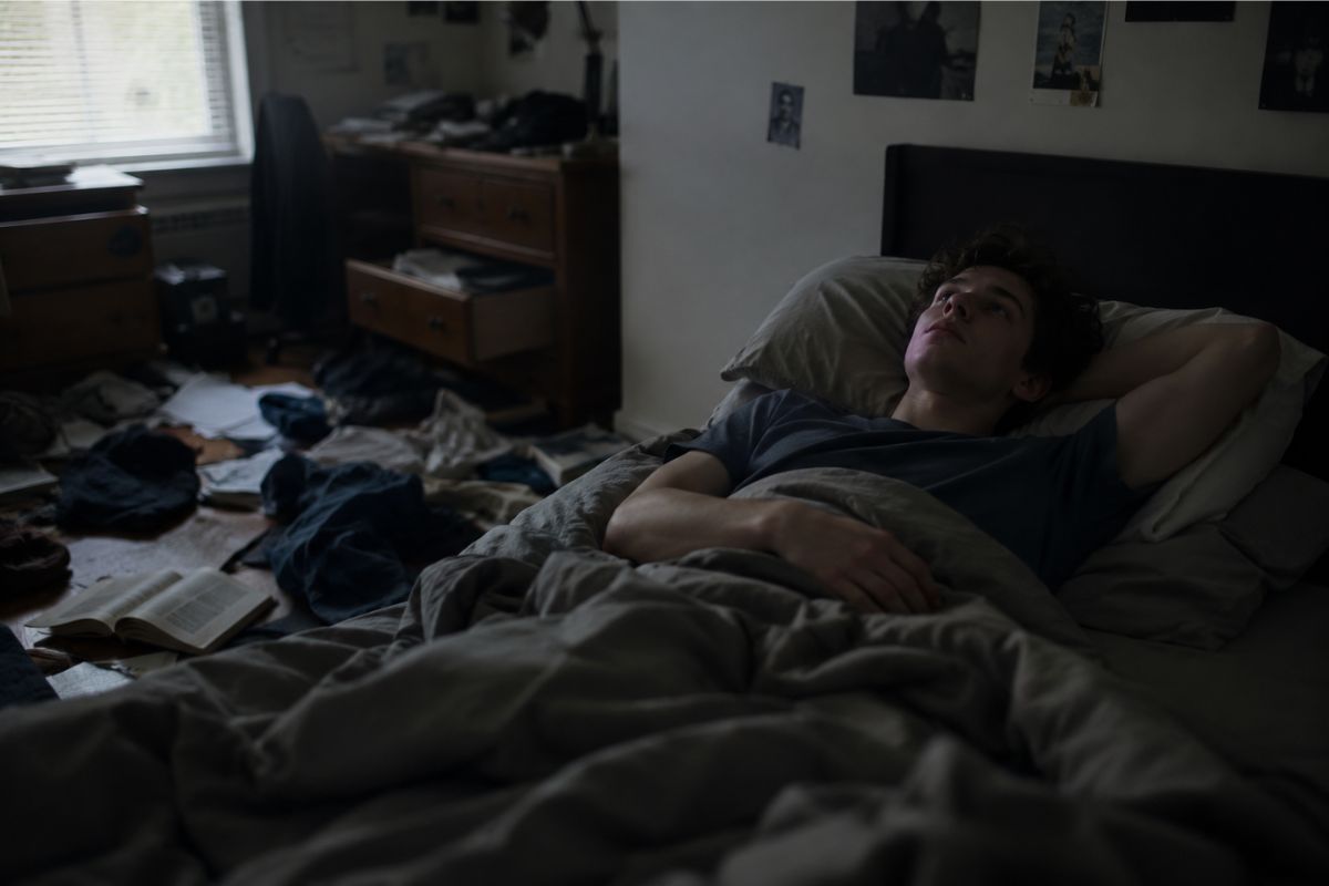 Um homem deitado na cama em seu quarto bagunçado tentando entender seus hábitos